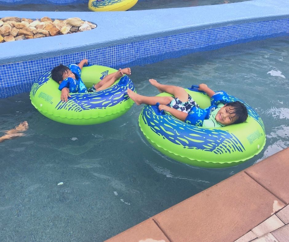 Two boys sitting in tubes floating around a lazy river