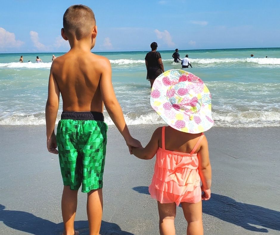 Little oy and girl holding hands by the ocean