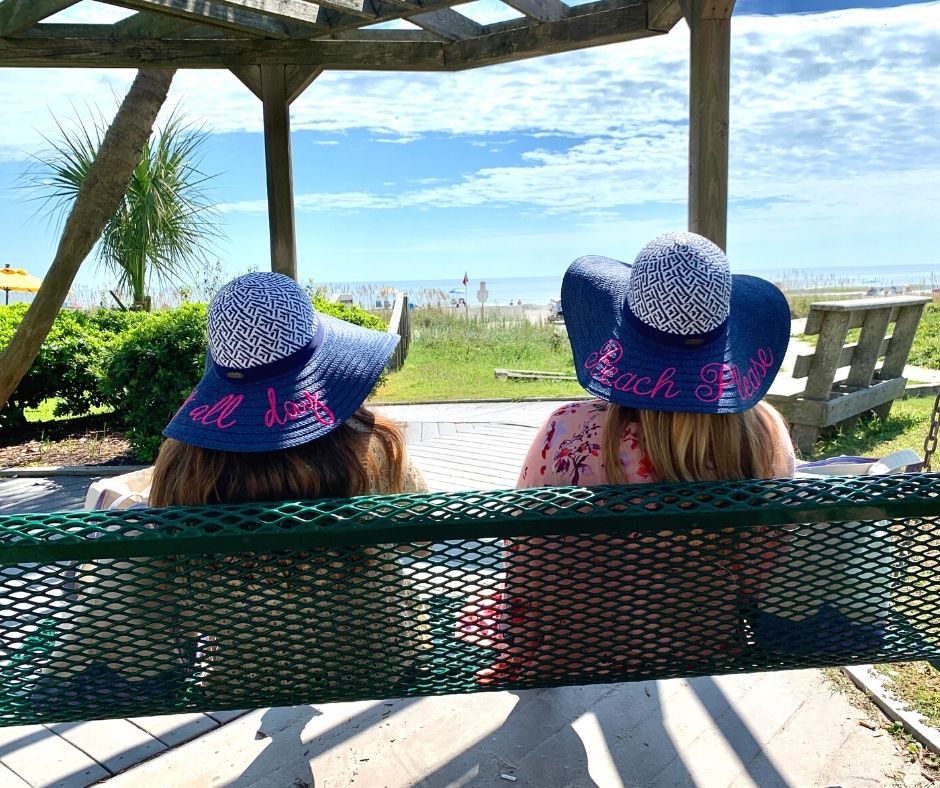 Two girls sitting on an oceanfront swing