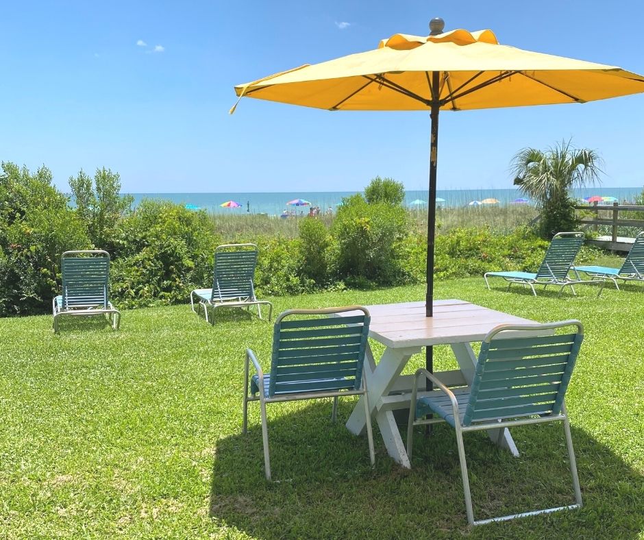 Up close of oceanfront yellow umbrella table and chairs