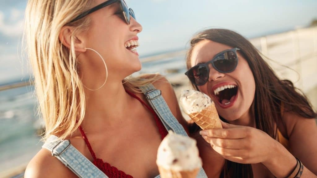 Two girls on the beach eating ice cream