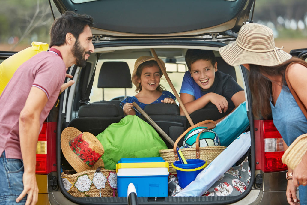 A family packing up the car for a road-trip to the beach.
