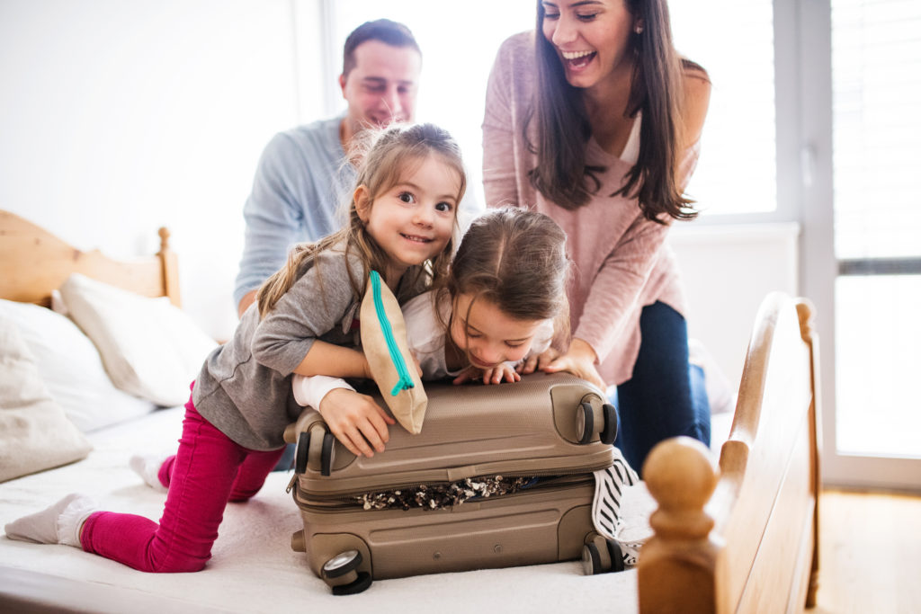 A family zipping their suitcase filled with things they need to bring on a beach vacation.